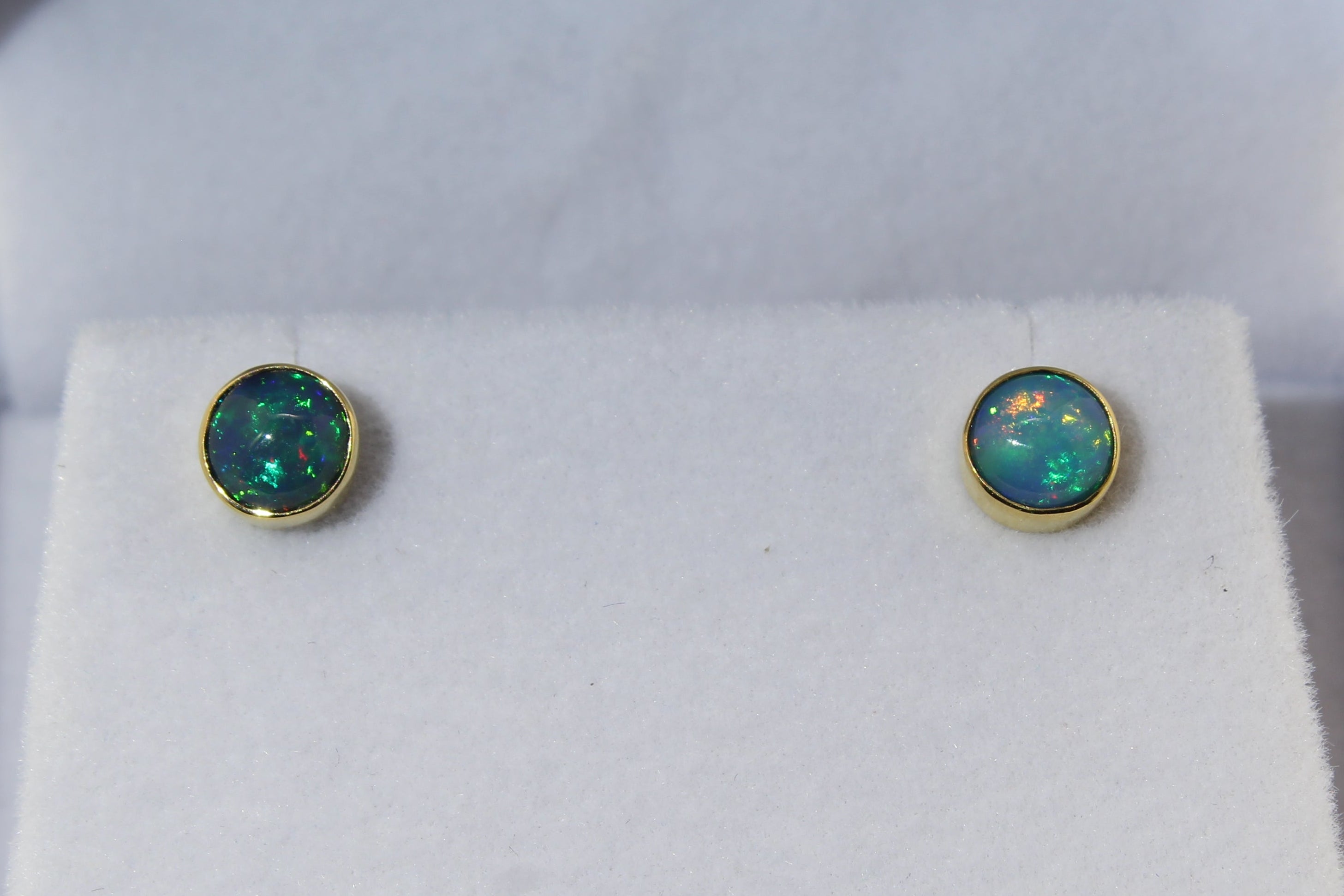 Opal stud earrings in a jewelry box on a white background