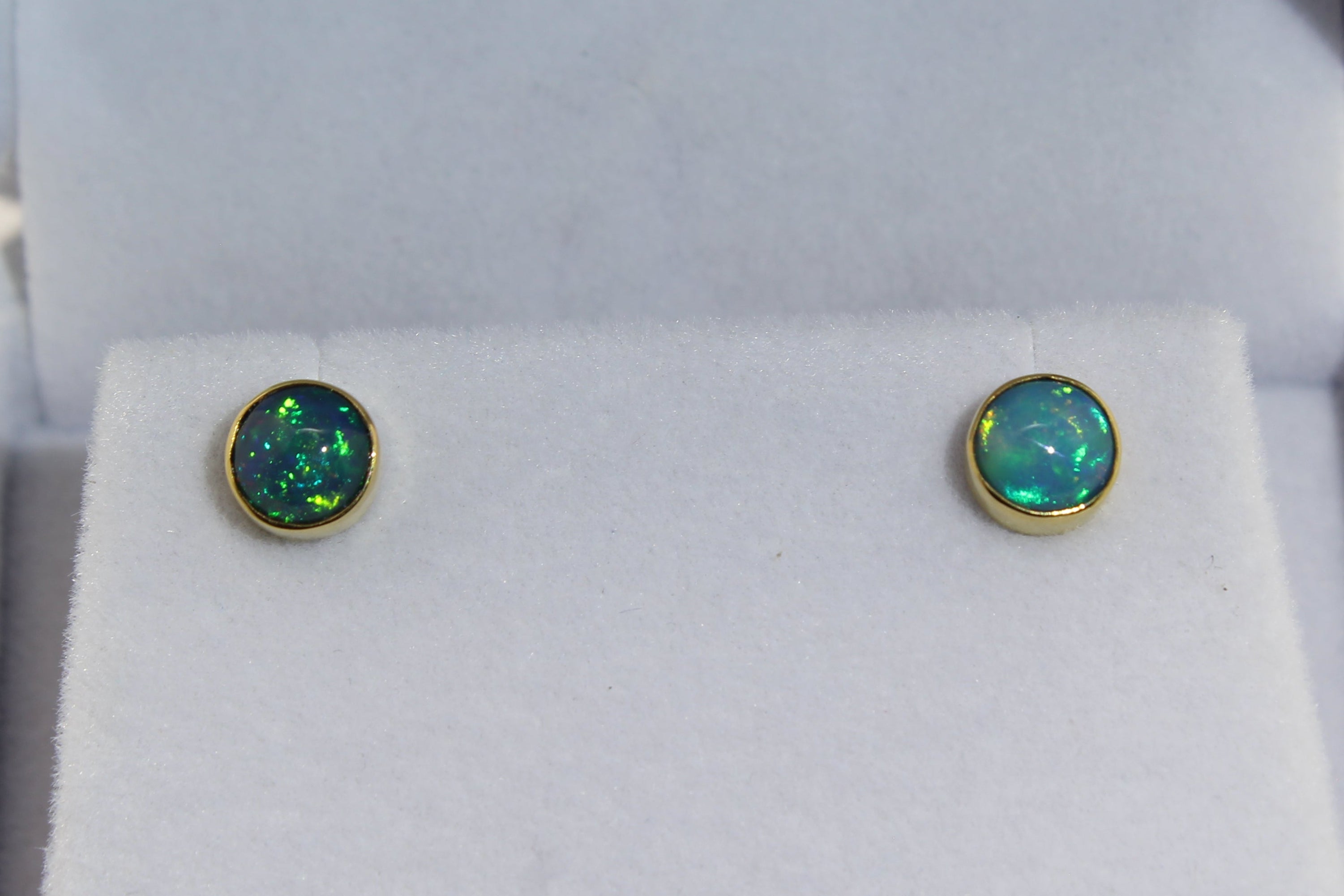 Gold opal stud earrings in a jewelry box