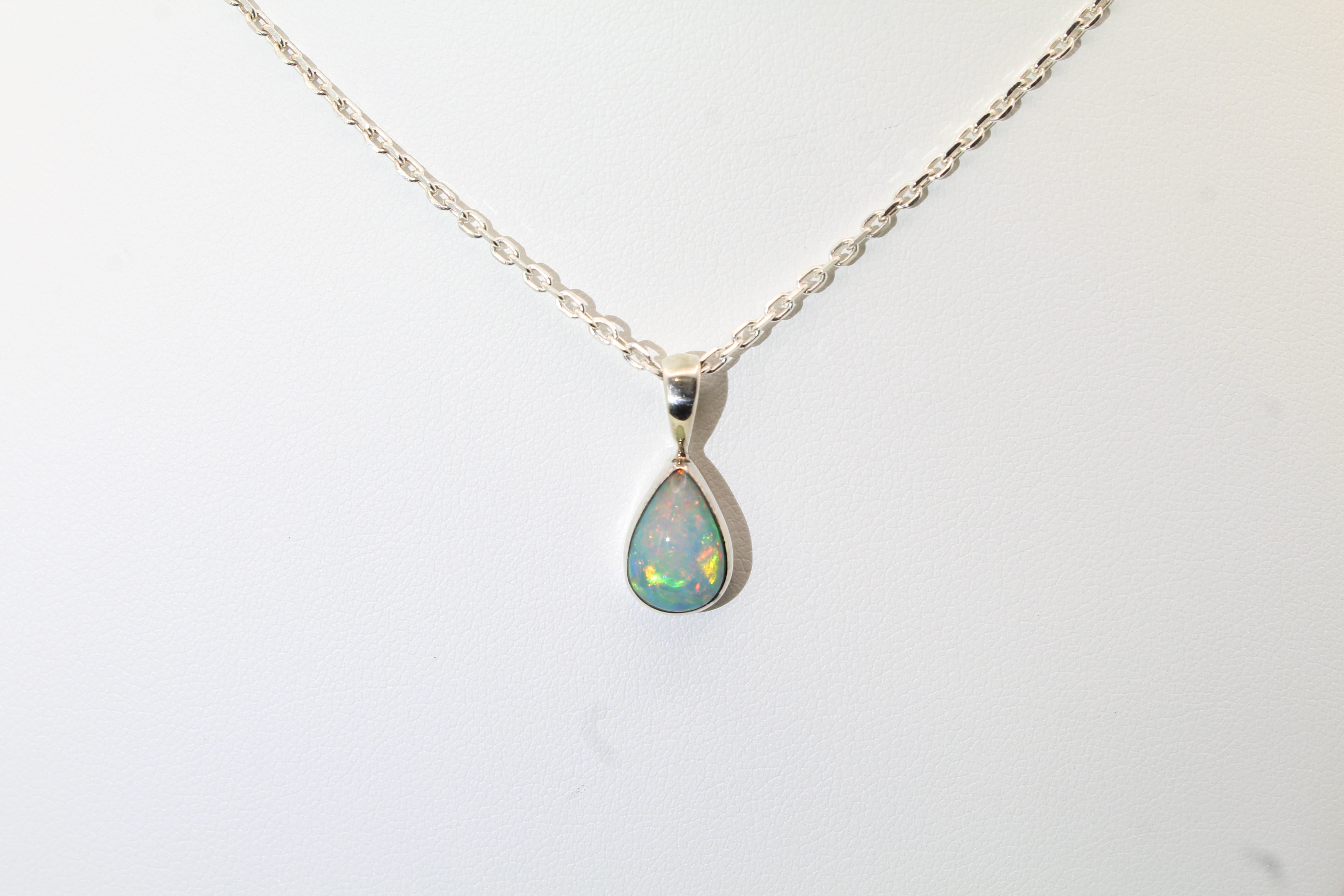 Teardrop-shaped opal pendant against a white background