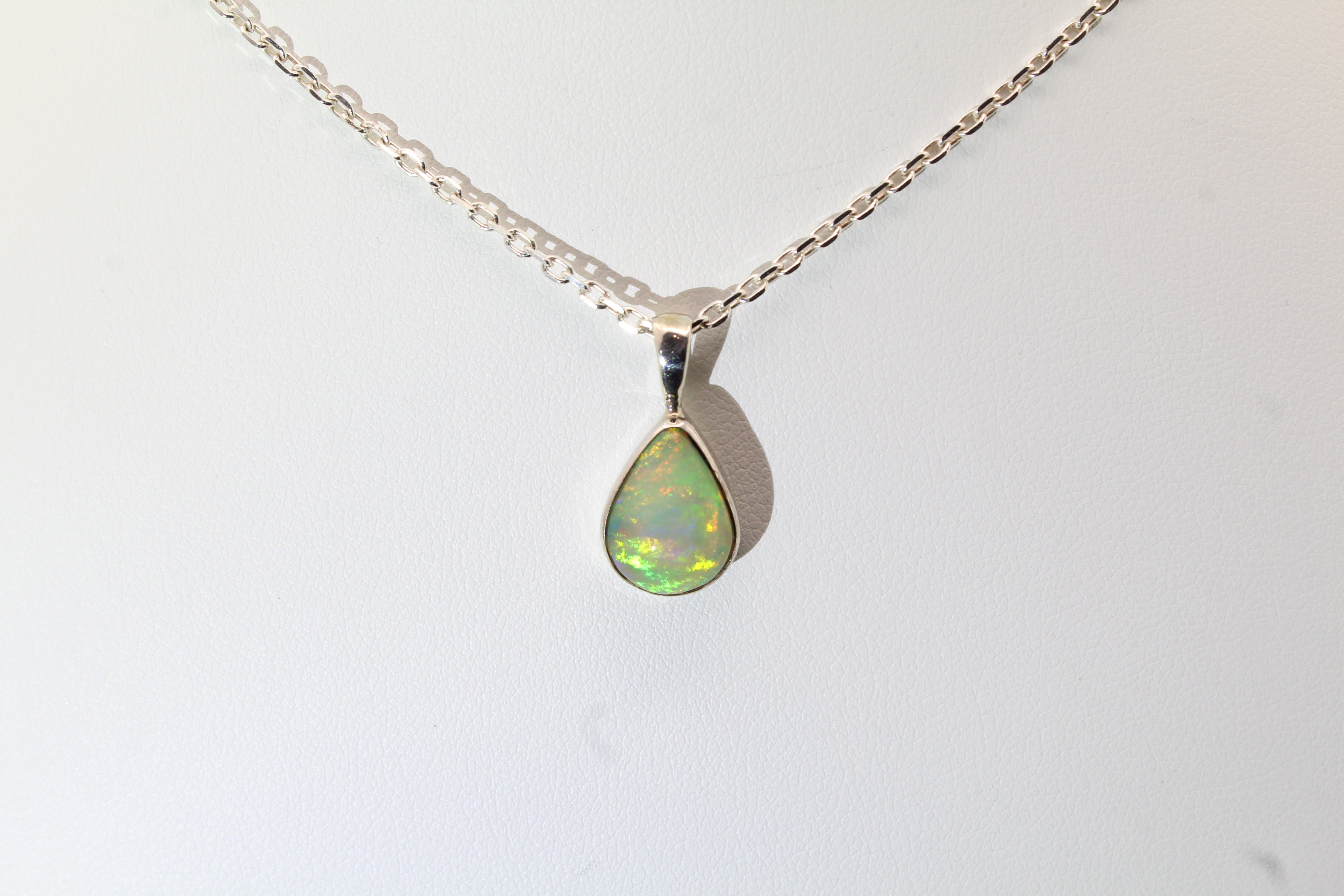 Opal teardrop pendant necklace on a white background