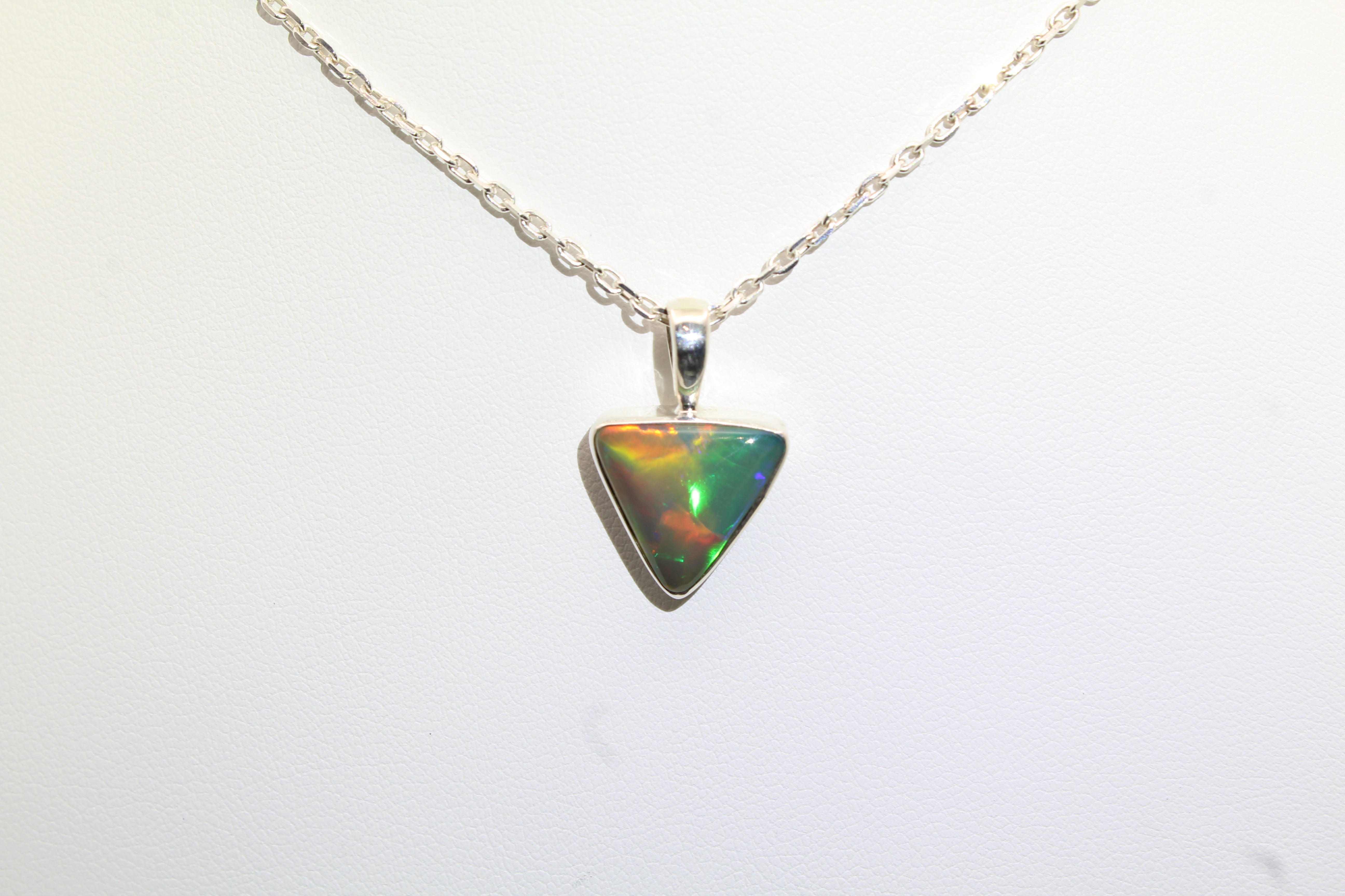 Triangular opal pendant on a silver chain against a white background